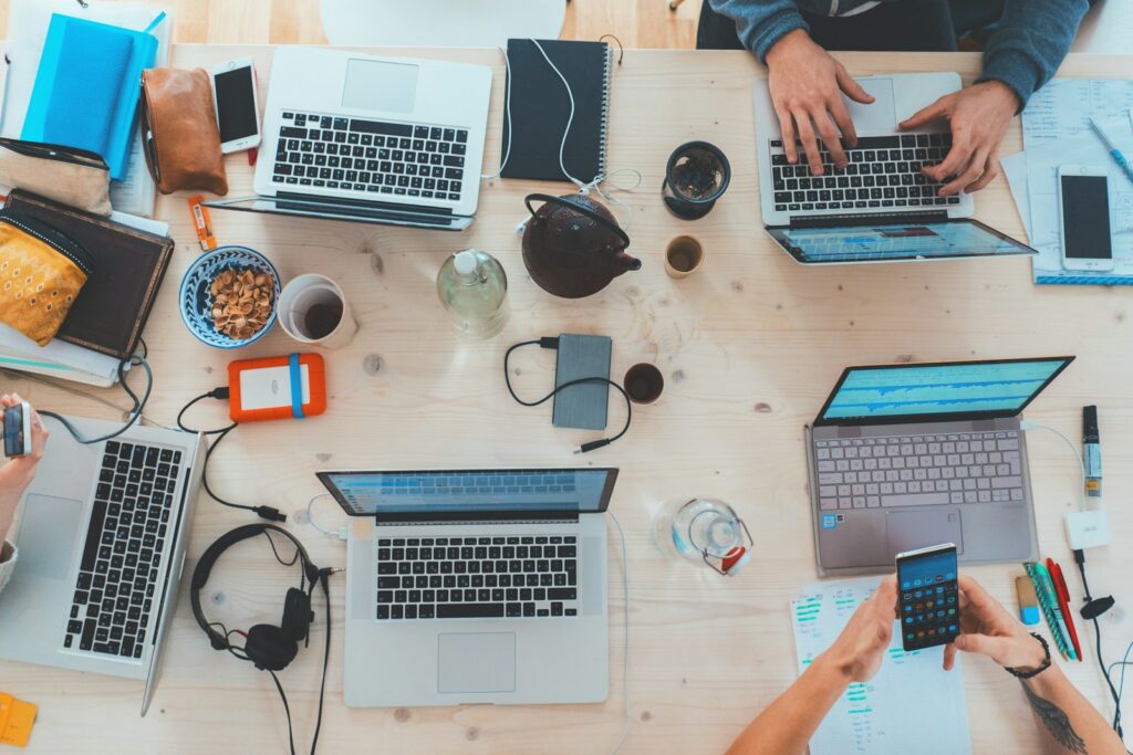 Small team working on laptops around a table with a shared project board