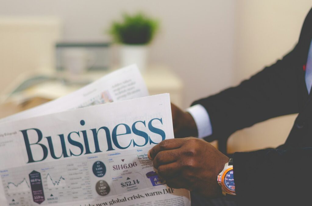 Person reading a business newspaper while planning freelance finances