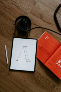 Tablet with a letter sketch and stylus, showing how to make a logo in Canva